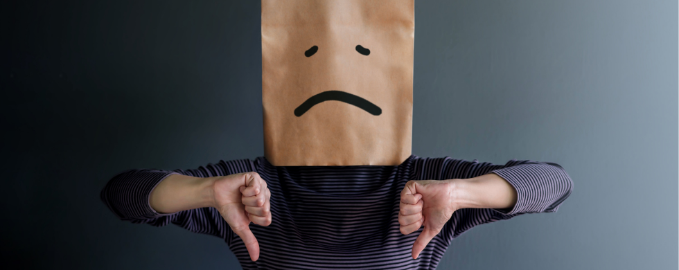 Person with a sad paper bag head and striped clothing shows thumbs down, symbolizing HVAC dissatisfaction.