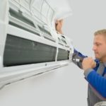 Technician repairing wall-mounted air conditioning unit with tools, focused on HVAC maintenance for homeowners.