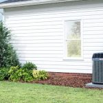 Well-maintained house with white siding and air conditioning unit, featuring landscaping by Boutwell's Air Masters.