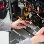 Technician repairing HVAC electrical components using a multimeter and vibrant wires.