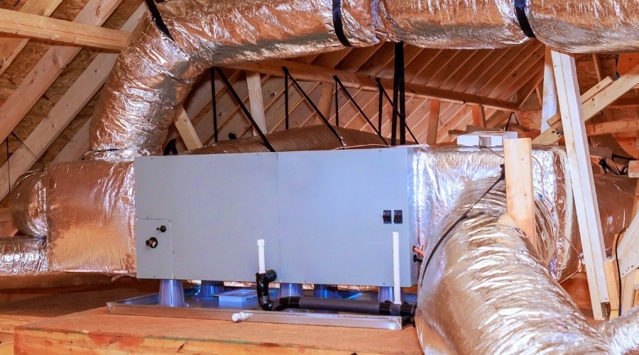 Air handler in attic with insulated ductwork and HVAC system components.